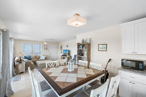 A dining area with a table, chairs, a guitar, and a microwave. - NEW to PROACTIVE Vacations! "Tri-D's" is a stunning 6 bedroom, 4 bathroom home WITH elevator! (Holden Beach)