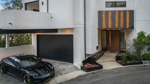 Ett modernt hus i två våningar med en svart bil parkerad framför.