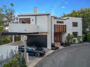 A modern two-story house with a garage, a car parked in front, and a well-maintained garden. - Franklin Modern (West Hollywood)