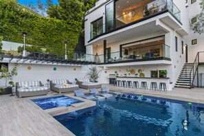 Una casa moderna de dos plantas con piscina, mobiliario exterior y zona de bar.
