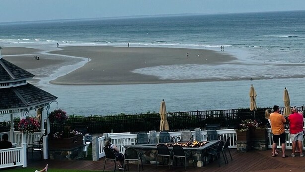 A beachside patio with outdoor seating, a gazebo, and a view of the ocean.