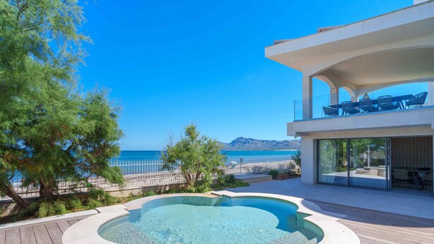A modern outdoor pool area with a clear view of the sea and mountains in the background. - Brand new house on the beach with panoramic views and a pool (Son Serra de Marina)