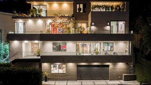 Una casa moderna de dos pisos con garaje, ventanas amplias y plantas en el exterior.