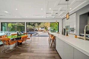Una cocina moderna con una isla grande, suelo de madera y vistas a una piscina y jardín.
