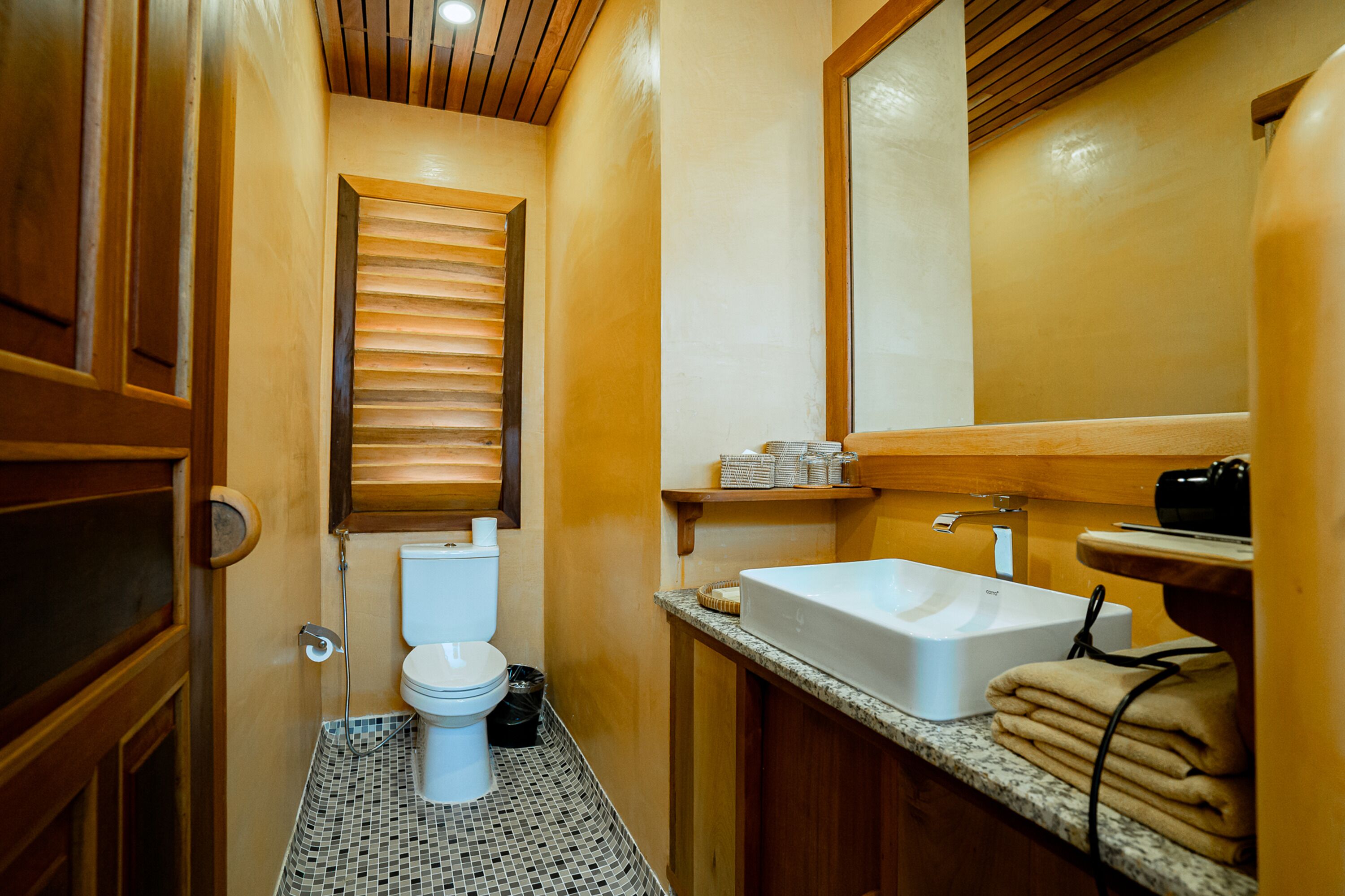 Une petite salle de bain comprenant des toilettes, un lavabo et un meuble-lavabo en bois.
