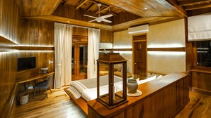 A wooden interior with a bed, a desk, a chair, a television, and a ceiling fan. - Peam Snea Resort (Kampot)
