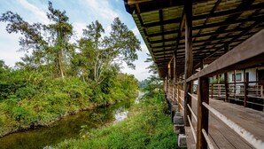A wooden deck with a view of a river and surrounding greenery. - Peam Snea Resort (Kampot)