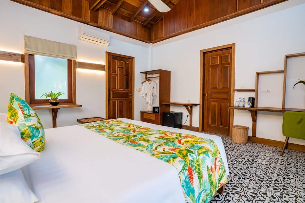 A hotel room with a bed, a desk, a chair, a wardrobe, and a window.