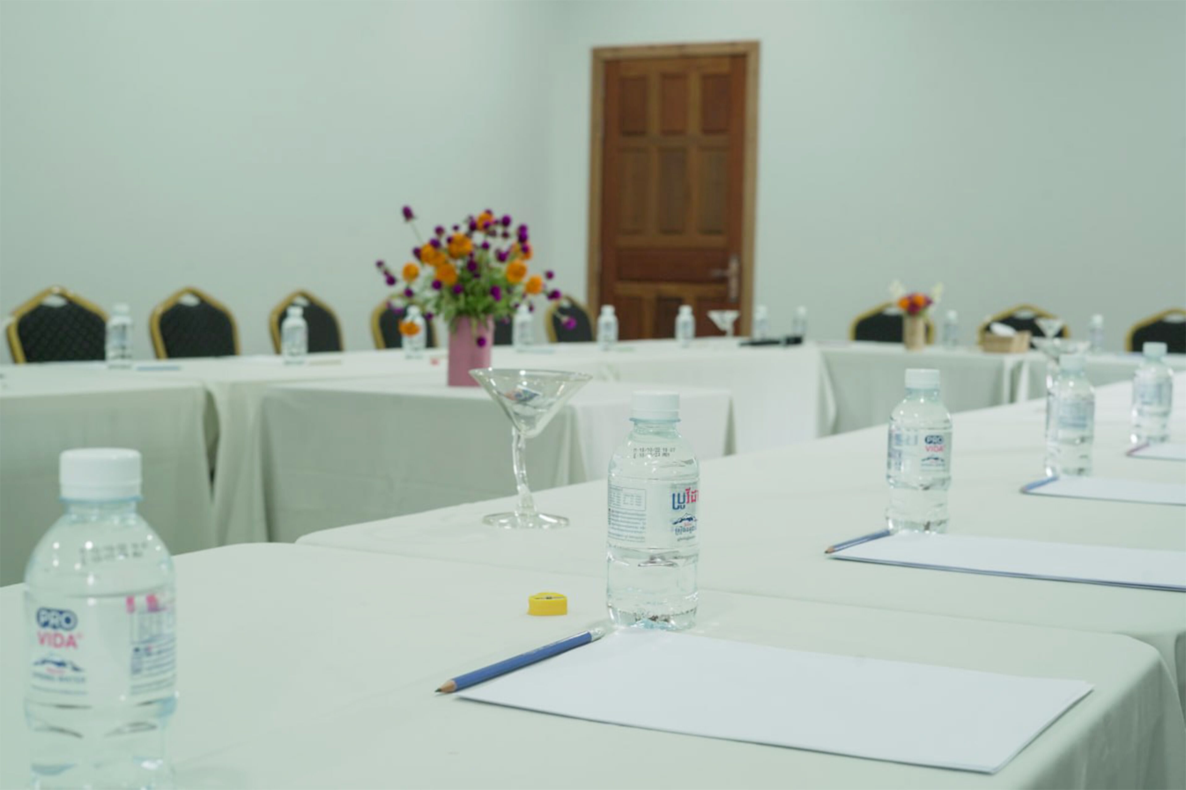 A conference room with tables set up for meetings, equipped with water bottles, pens, and notepads.