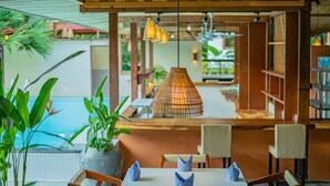 A restaurant with a pool view, wooden ceiling, and hanging lights. - Peam Snea Resort (Kampot)