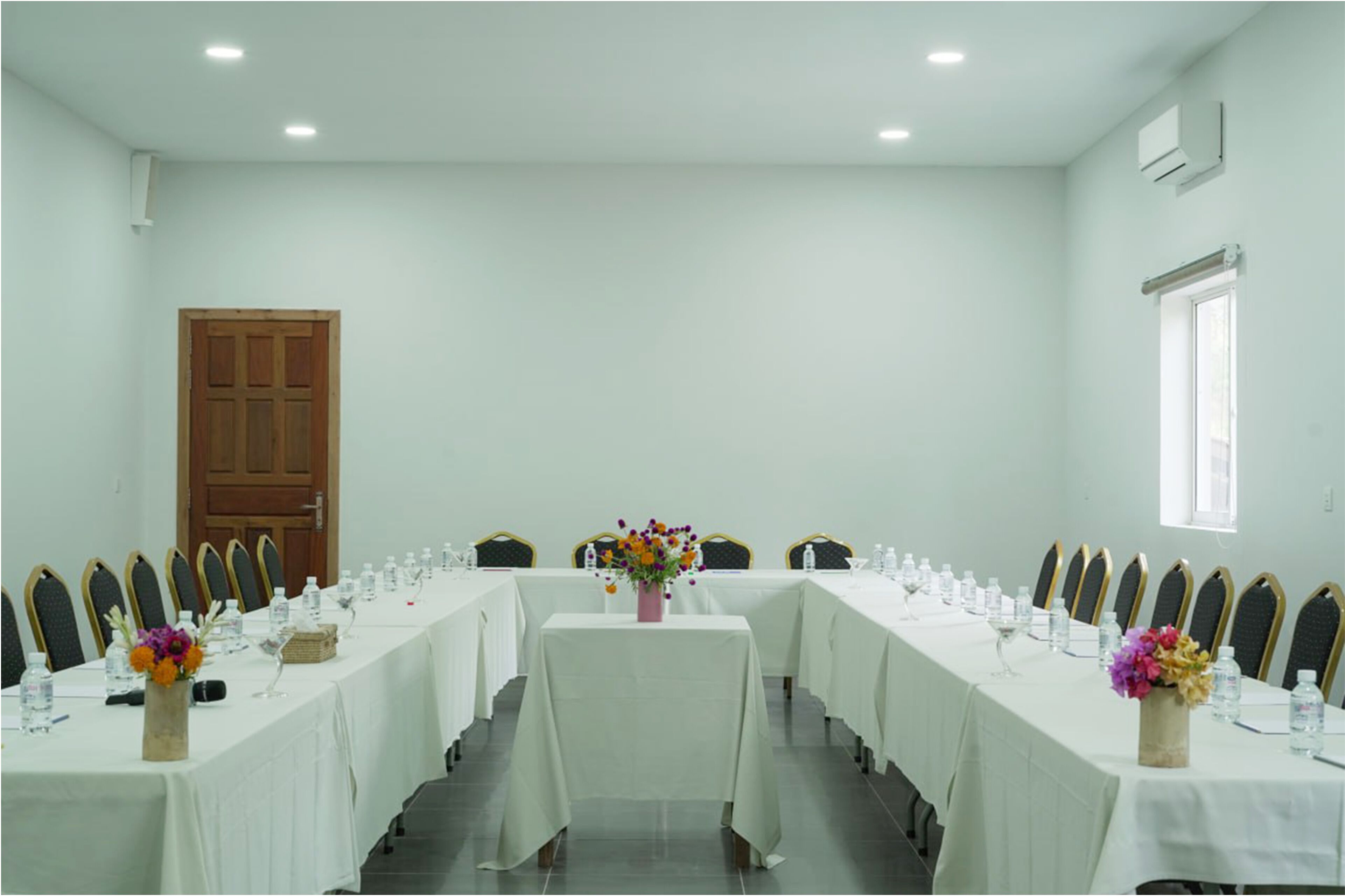 A conference room with a long table, chairs, and floral centerpieces.