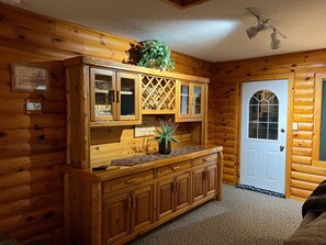 Cozy cabin interior features a central cabinet with glass doors and a potted plant on the countertop.