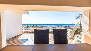 A balcony with two chairs, a table, and a satellite dish.
