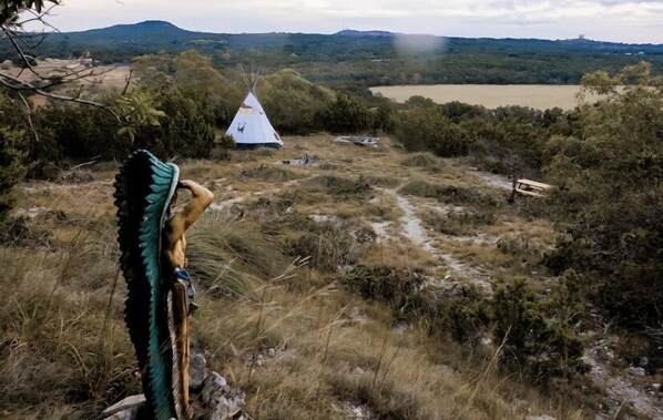 A white teepee in a natural landscape with a path leading to it.