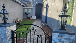 A gated entrance with a tiled roof, a small garden, and a pathway leading to a door.
