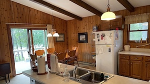 A kitchen with wooden walls, a central island with a sink, and a refrigerator. - Stunning views on tranquil lake. (Crosslake)