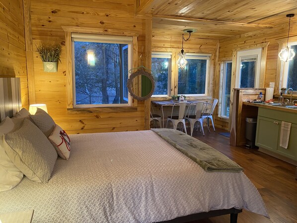 L’intérieur d’un chalet confortable, avec un lit, une table à manger, des chaises et un coin cuisine.