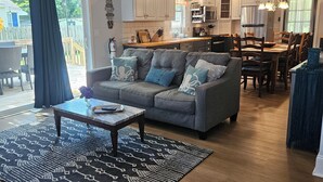 Ein modernes Wohnzimmer mit einem grauen Sofa, einem Couchtisch und einem gemusterten Teppich.