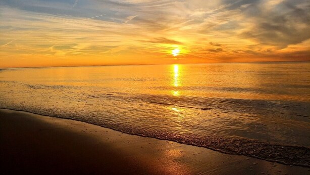 Eine Strandansicht mit Sonnenuntergang über dem Wasser.