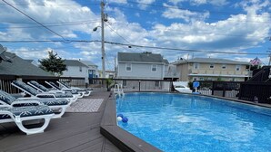 Una piscina con sillones de descanso y una terraza de madera.