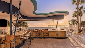 A bar area with a curved ceiling, a flat-screen TV, and outdoor seating.
