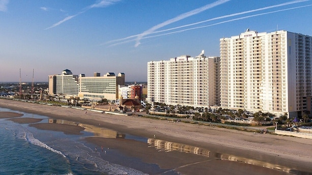 A coastal cityscape with high-rise hotels, a beach, and a pier.