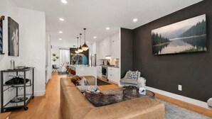 A modern living room with a leather sofa, a dining area, and a kitchen. - Group-Friendly 2 Nashville Homes • Sleeps 15 (Nashville)