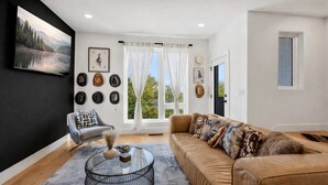 A modern living room with a leather sofa, a glass coffee table, and a grey armchair. - Group-Friendly 2 Nashville Homes • Sleeps 15 (Nashville)