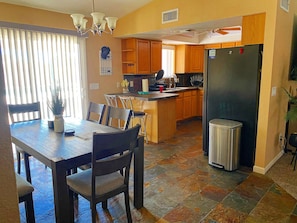 A compact kitchen with wooden cabinets, a refrigerator, and a dining area with a table and chairs. - COZY HAVASU OASIS just minutes from the lake And all shopping! (Lake Havasu City)