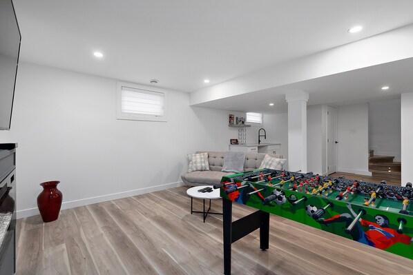 A spacious living room with a foosball table, a sofa, and a coffee table.