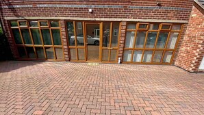 A brick-paved courtyard with a building featuring large windows and a car parked inside.