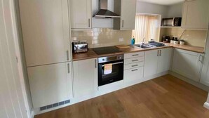A compact kitchen with white cabinets, a built-in oven, a microwave, and a wooden countertop.