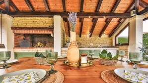 A rustic dining area with a wooden table set for four, surrounded by woven placemats and a central vase with flowers.