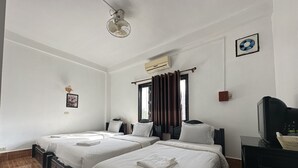 A hotel room with two beds, a ceiling fan, an air conditioning unit, a television, and a window with curtains. - VangVieng Santara Hotel (Vang Vieng)