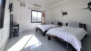 A hotel room with two beds, a window with curtains, an air conditioning unit, a small table with a lamp, and a wall-mounted picture. - VangVieng Santara Hotel (Vang Vieng)