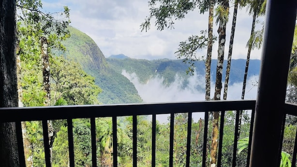 En balkong med utsikt över frodig grönska och ett vattenfall.