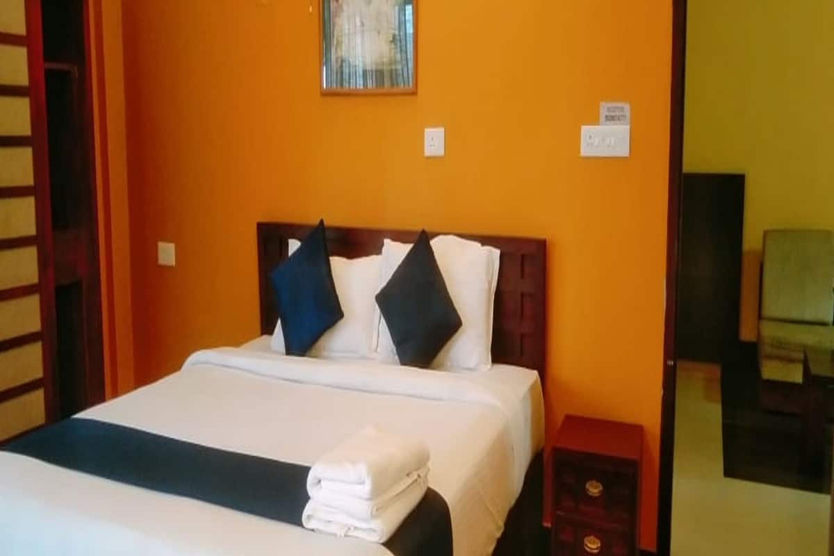 A hotel room with a bed, a nightstand, and a small table.