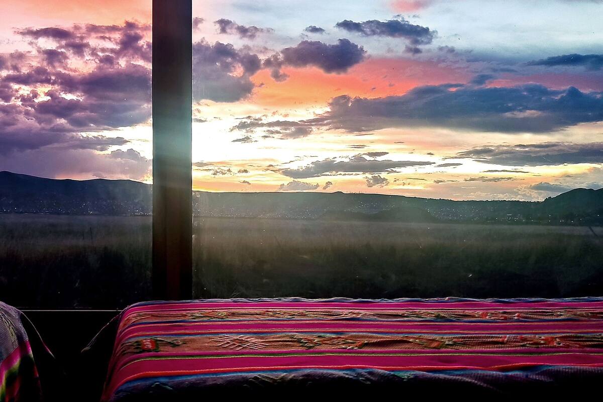Une chambre avec deux lits et une vue sur les montagnes et le coucher de soleil.