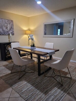 Enjoy meals in this stylish dining area with a beautifully set table, comfortable chairs, and a large mirror above.