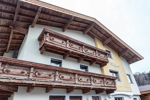 A multi-story building with wooden balconies, a sign reading 'Haus Bergwirt,' and a window labeled 'Restaurant - Zimmer.'
