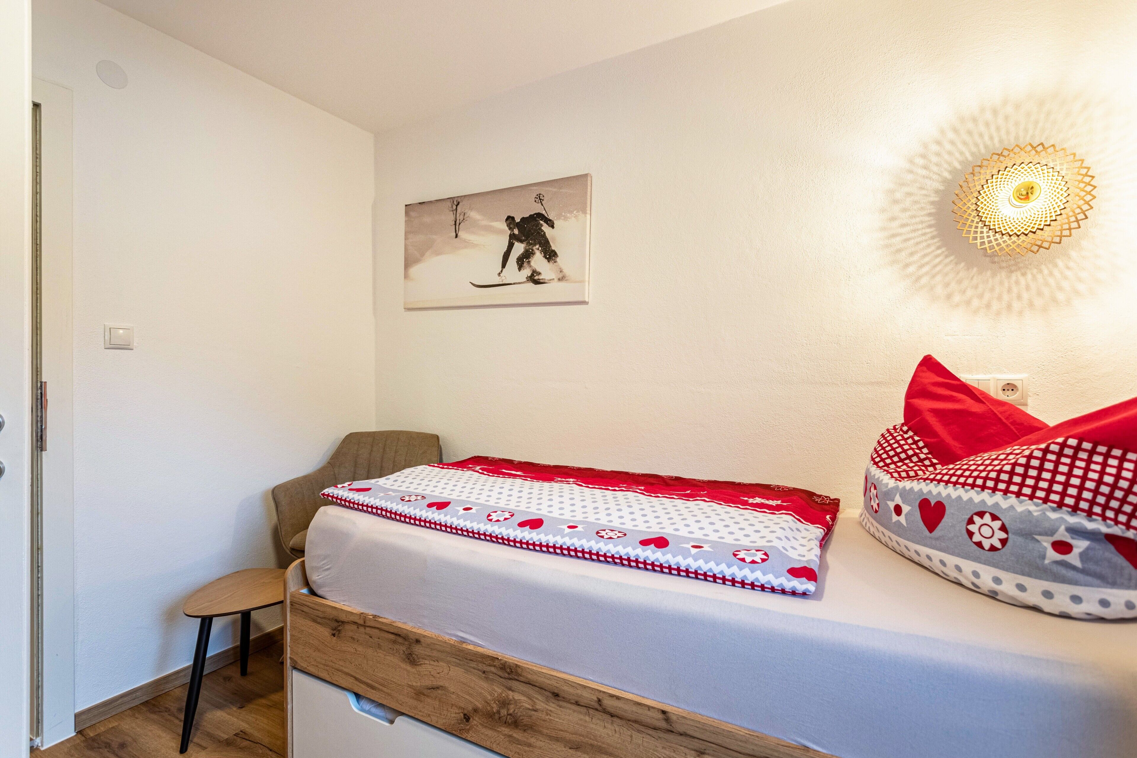 Een slaapkamer met een bed, een stoel, een wandlamp en een schilderij.