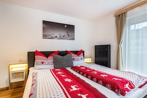 Ein Schlafzimmer mit einem Bett, Kissen, einem Nachttisch, einem Wandbild und einem Fenster mit Vorhängen.