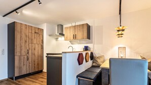 A modern kitchen with wooden cabinets, a built-in island, and pendant lighting. - Apartment 'Bergwelt A2' with Mountain View, Balcony and Wi-Fi (Niederau)