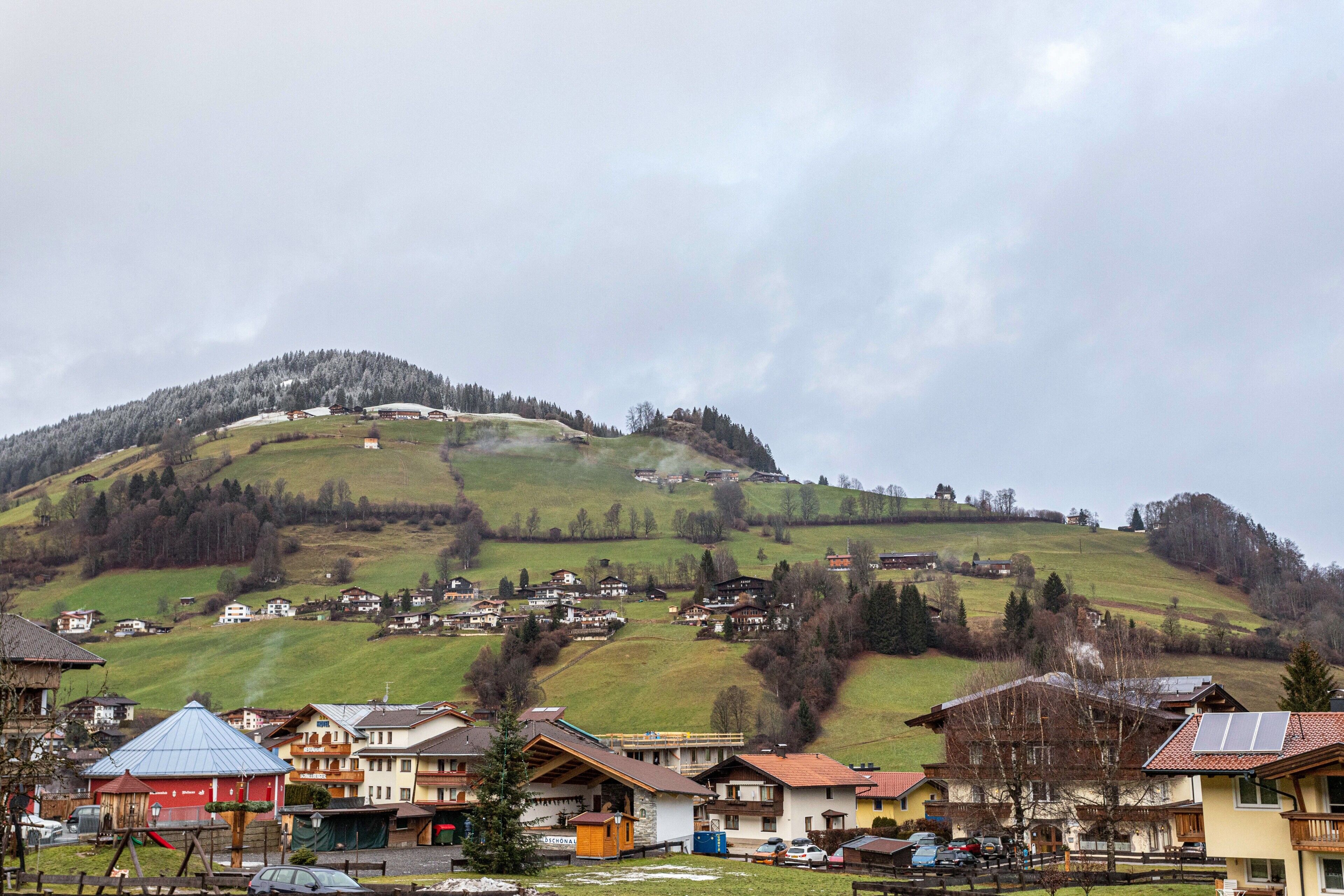 A village with houses on a hillside, a playground, and a building with a blue roof.