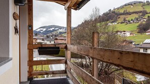 Ein Holzbalkon mit Blick auf ein Hügeldorf.