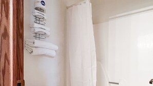 A bathroom with a toilet, a shower curtain, and a towel rack.