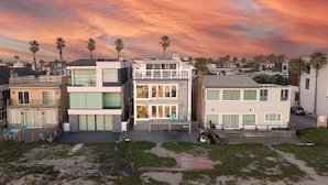 A modern residential area with multiple two-story houses, a patio with outdoor furniture, and palm trees.