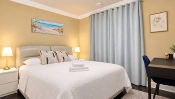 A hotel room with a bed, bedside lamps, a desk, and a chair.