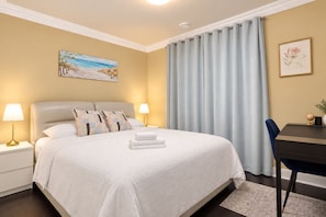 Een hotelkamer met een bed, nachtlampjes, een bureau en een stoel.