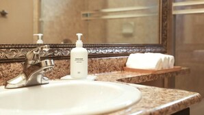 A bathroom with a marble countertop, a white sink, a silver faucet, and a hand soap dispenser. - Cozy King Sized Private Entrance Suite 15 min from YVR and self check in (Richmond)